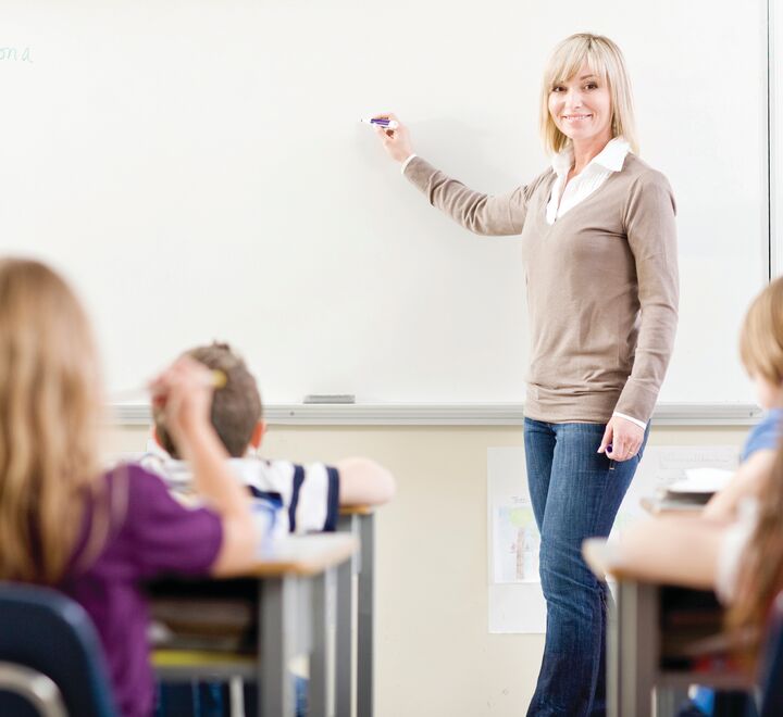 Bilde av en lærer foran skolebarn.