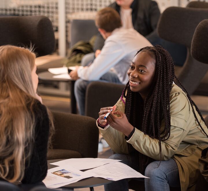 To kvinnelige studenter som sitter å snakker sammen