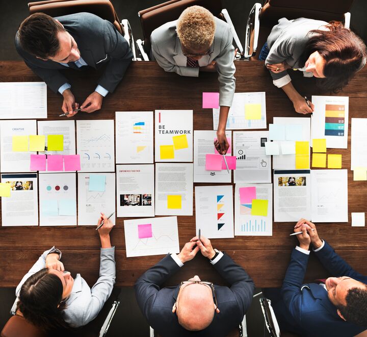 Mennesker rundt et bord med dokumenter sett ovenfra