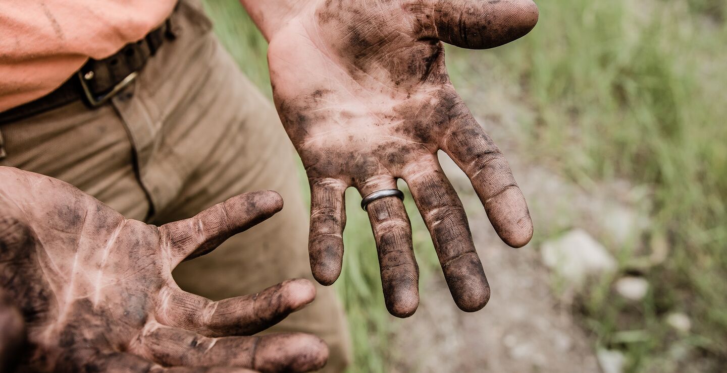Man with hands covered in mud.