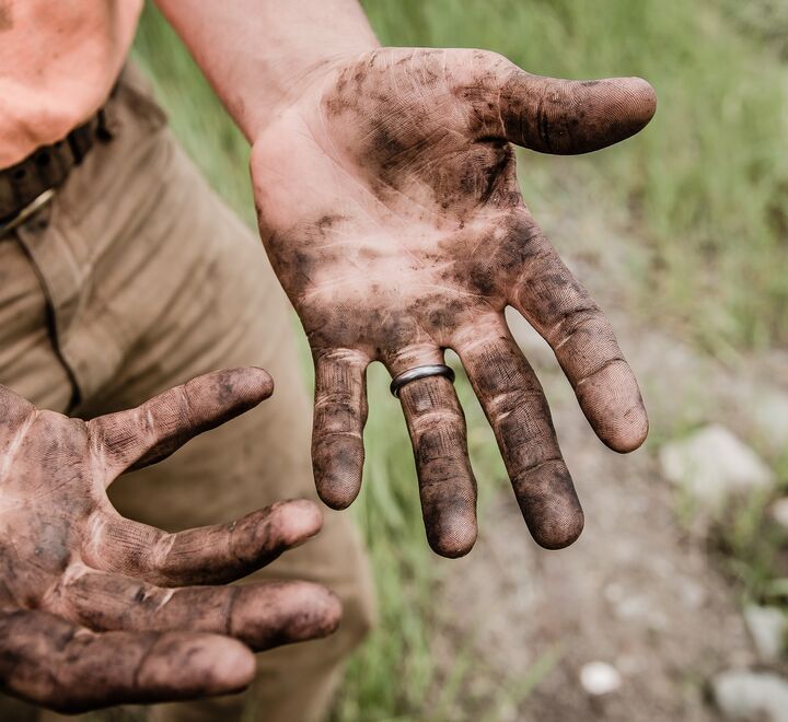 Man with hands covered in mud.
