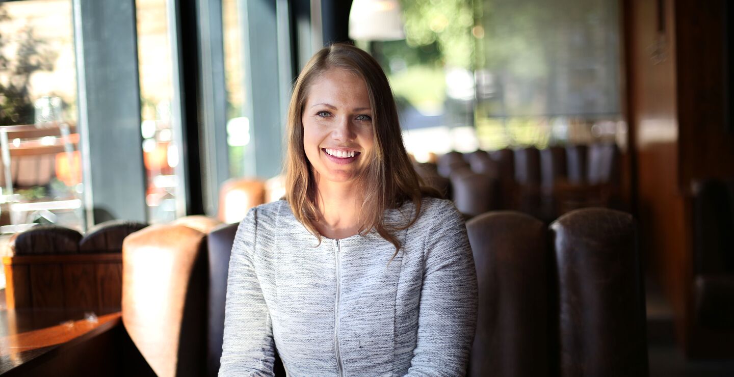 Ide Katrine Birkeland som sitter i en sofa i en resturant og smiler