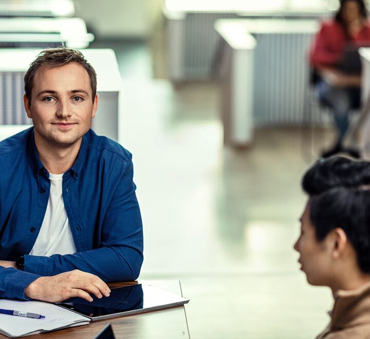 En mannlig student i blå skjorte på campus