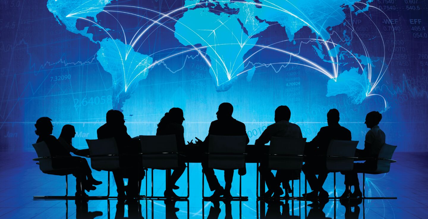 Mennesker i et møterom foran et verdenskart.