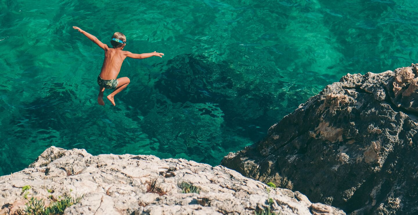 Bilde av gutt som stuper i grønt vann. (Foto: Nikola Radojcic, Unsplash.com).