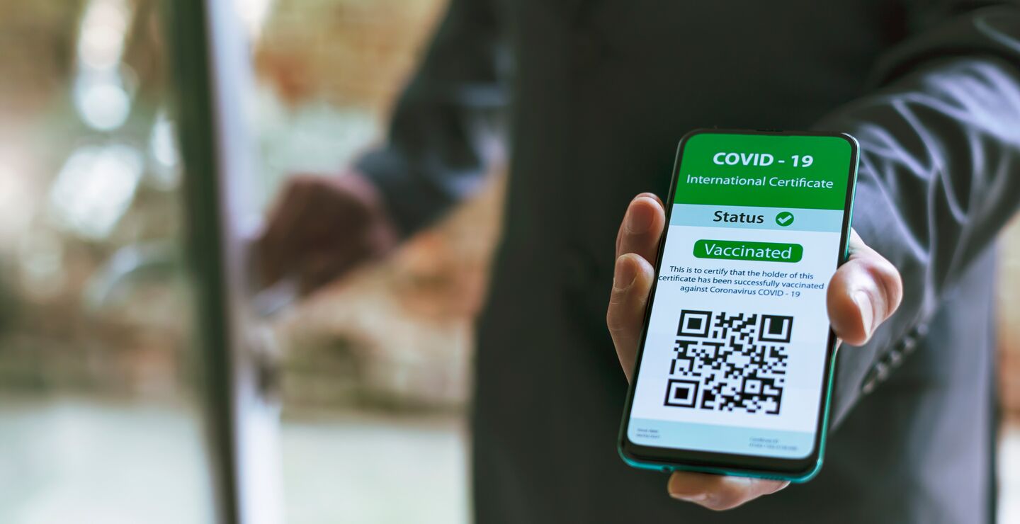 Mann viser frem internasjonalt koronasertifikat på telefonen sin.