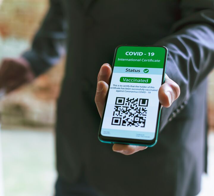Mann viser frem internasjonalt koronasertifikat på telefonen sin.