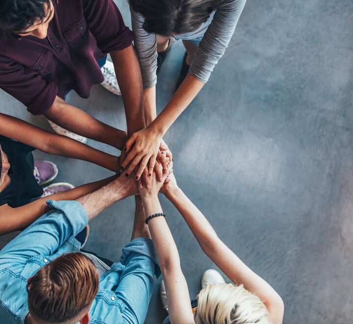 Mennesker som står sammen og holder hender