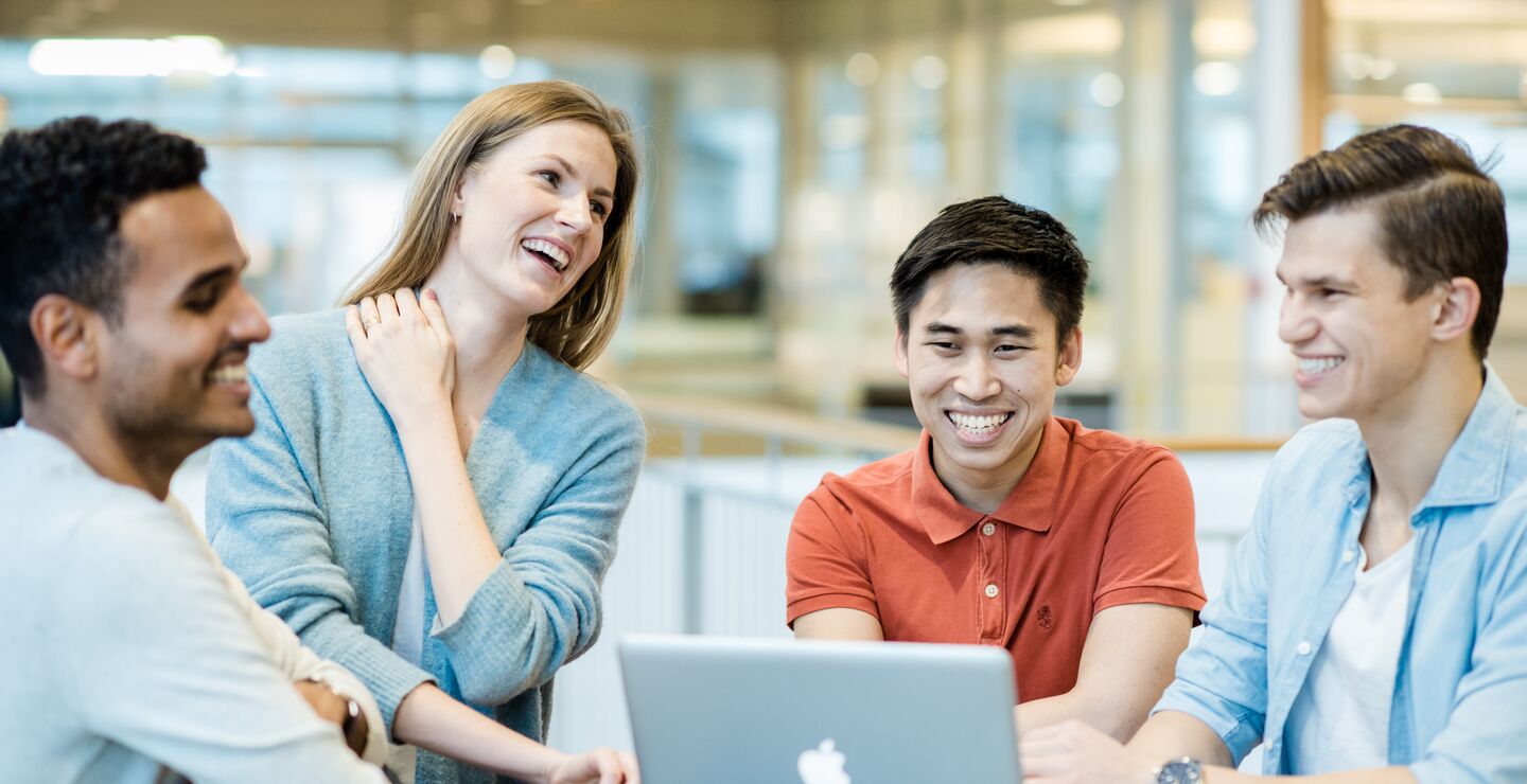 Smilende kolleger samlet rundt et bord 