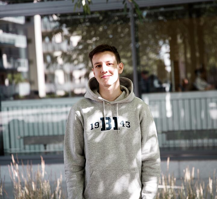 Smilende mann i grå BI-genser