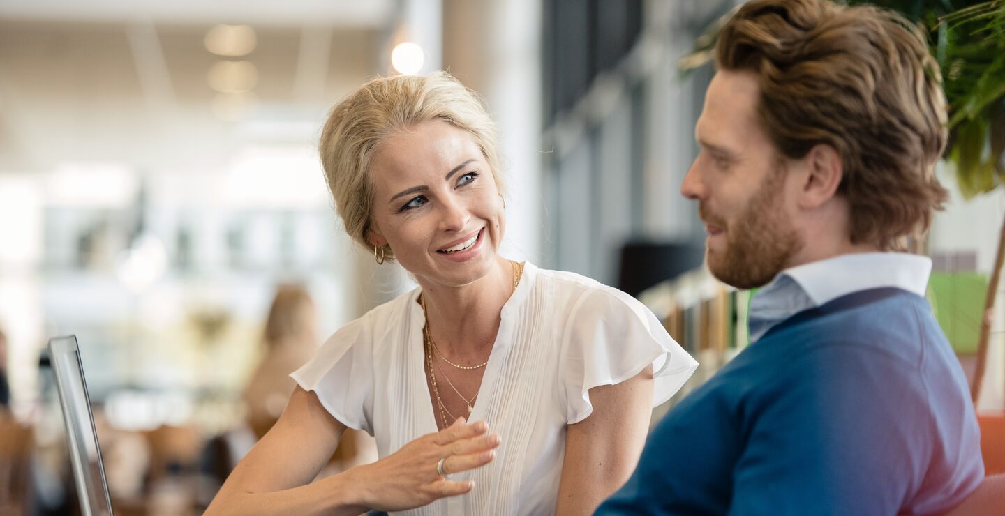 A woman explaining something to a man working on his laptop