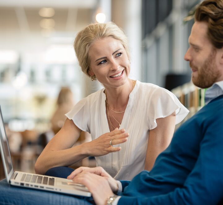 A woman explaining something to a man working on his laptop