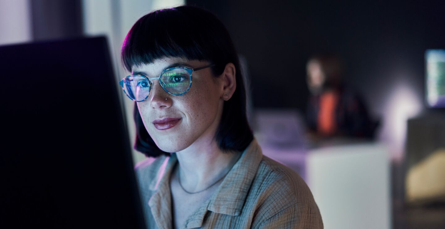 A woman working in front of a computer screen.