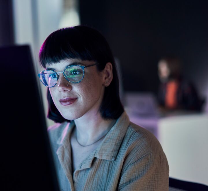 A woman working in front of a computer screen.