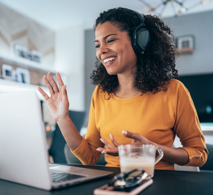 En dame som jobber på en laptop med kaffe i hånda