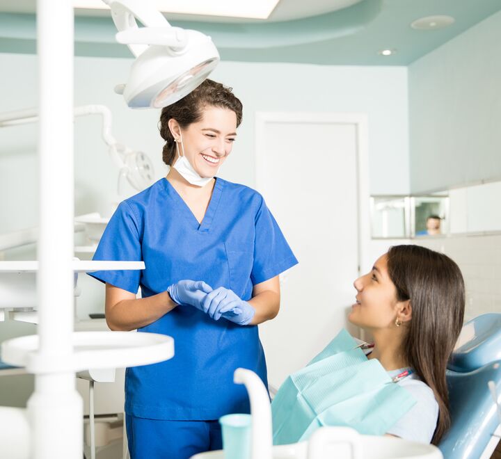 Smilende tannlege snakker med pasient