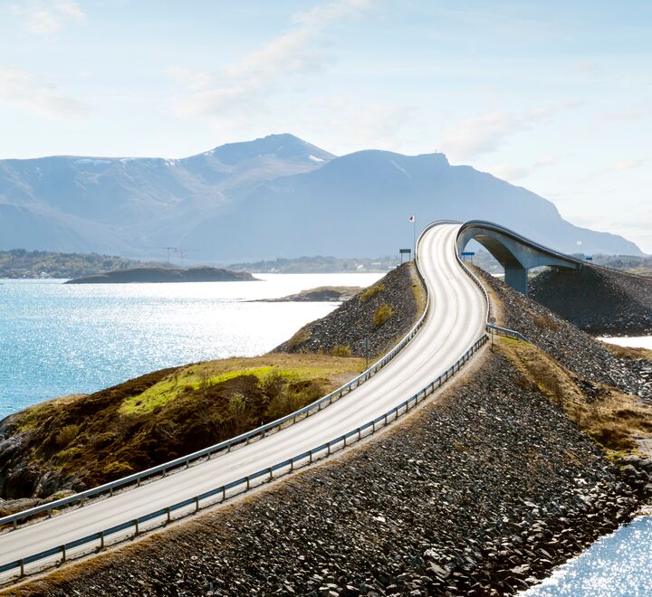 Vei med hav og fjell i bakgrunnen