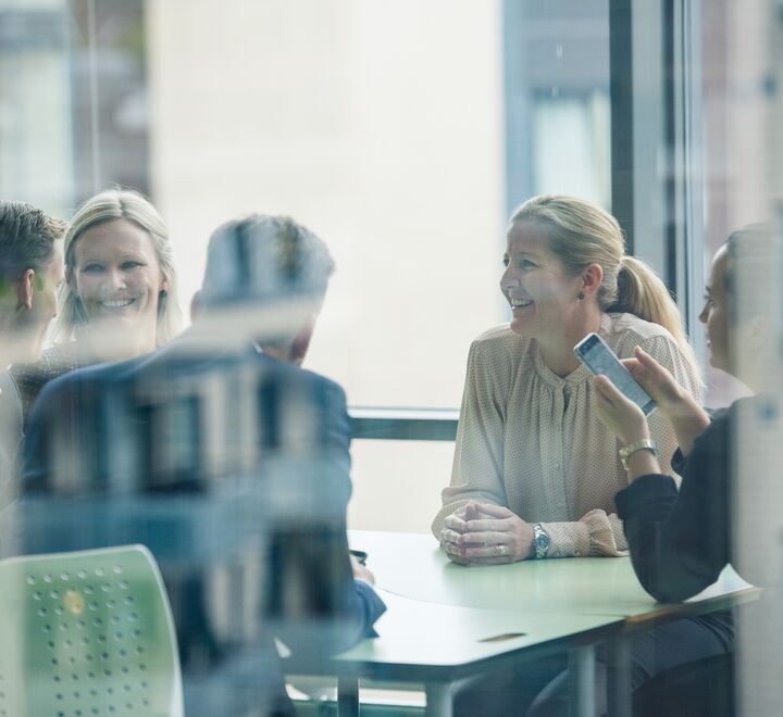 Bilder av ansatte som sitter i en gruppe og diskuterer