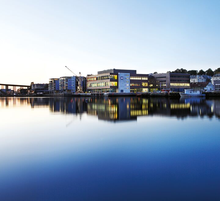 Utenfor campus Bergen. Bilde av vannet og en bro, med BI-bygget i midten.