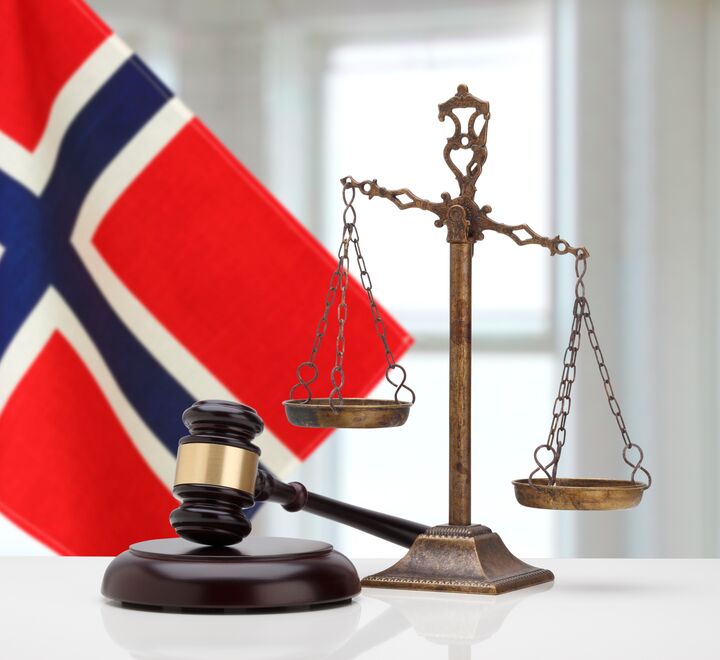 Bilde av dommerklubbe med det norske flagg i bakgrunnen