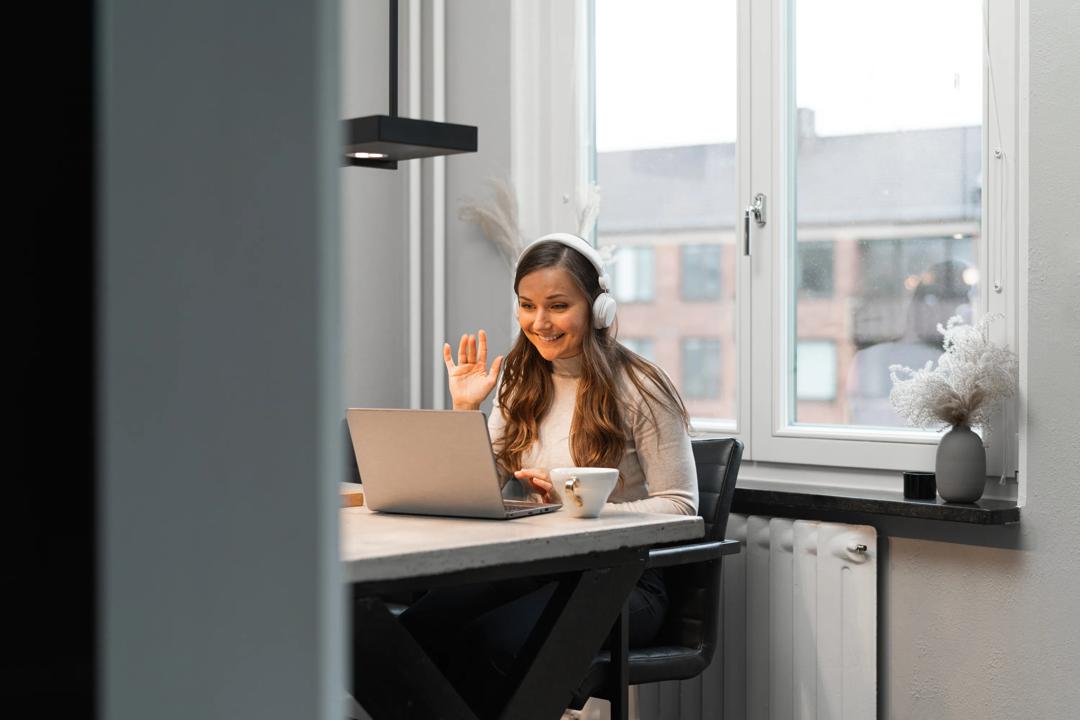Kvinne med laptop og headset deltar i digitalt møte fra hjemmekontoret. Foto: Getty Images