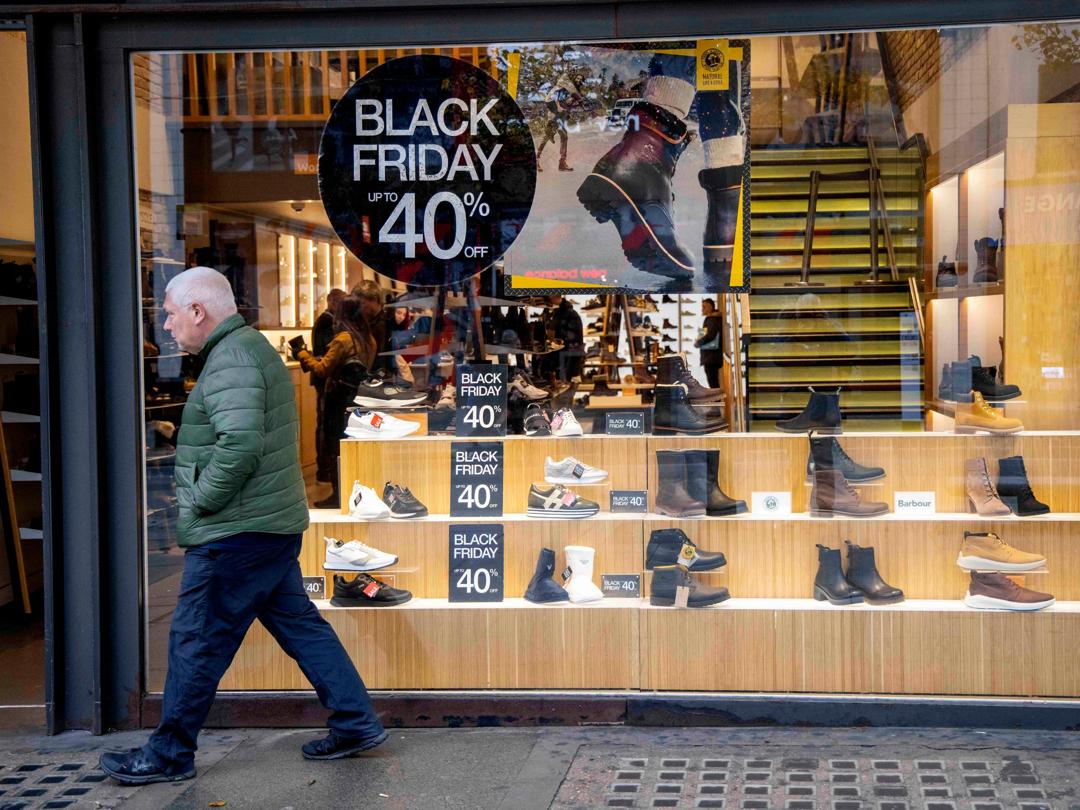 En mann passerer et butikkvindu med Black Friday-reklame.