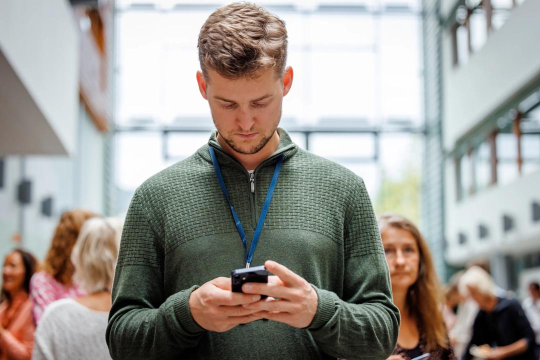 Mann som ser ned på mobilen sin