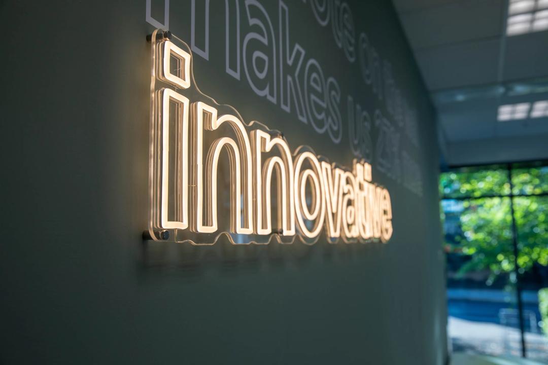 Led lys som henger på veggen hos The Village. Det står "Innovative".