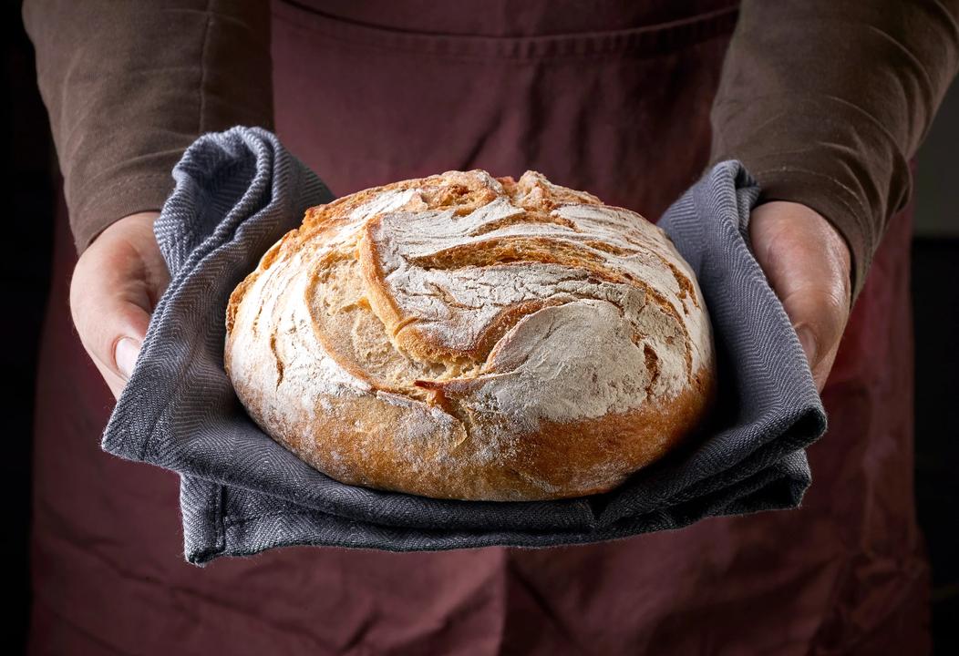 Freshly,Baked,Bread,In,Bakers,Hands
