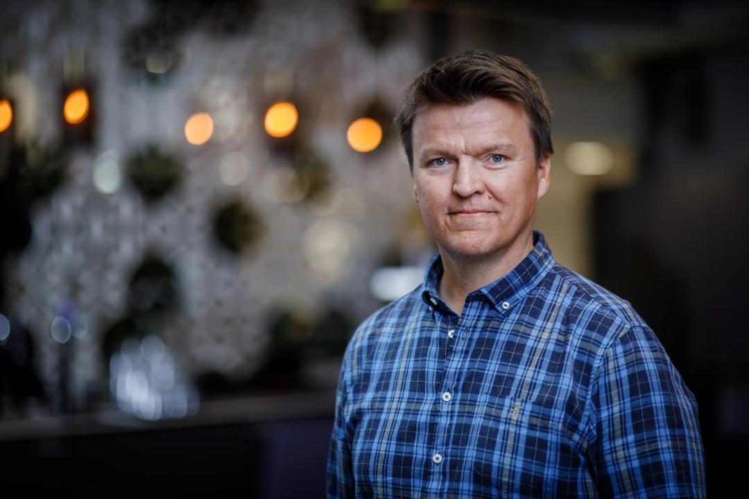 Bilde av en smilende mann i rutete blå skjorte