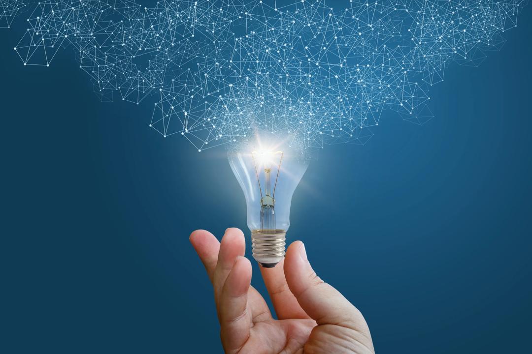 Blue background with a hand holding a light bulb. The light bulb is on and lights up.