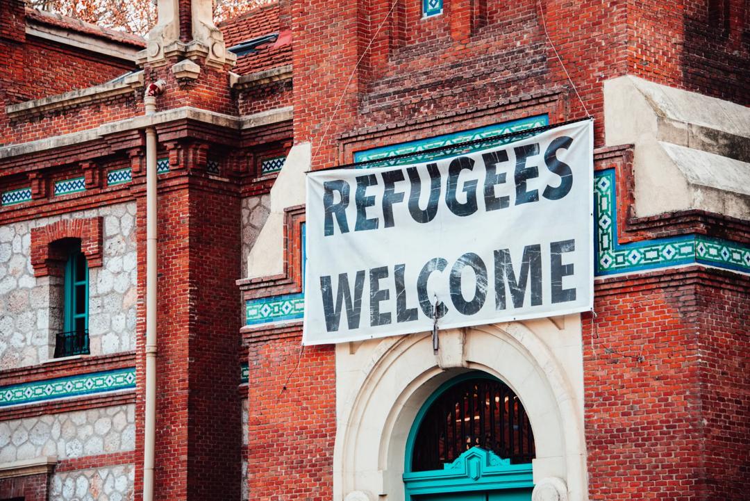 "Refugees Welcome" banner hanging on brick building
