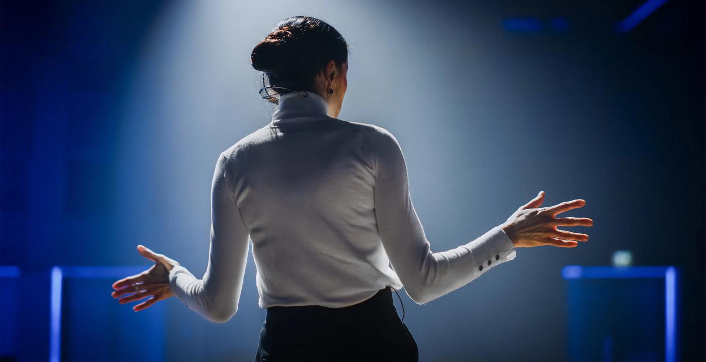 Bilde av en dame som holder et foredrag i et auditorium
