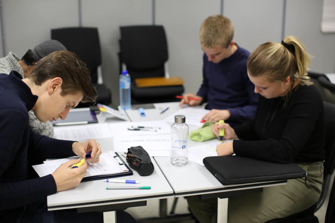 Tre studenter som sitter å studerer.