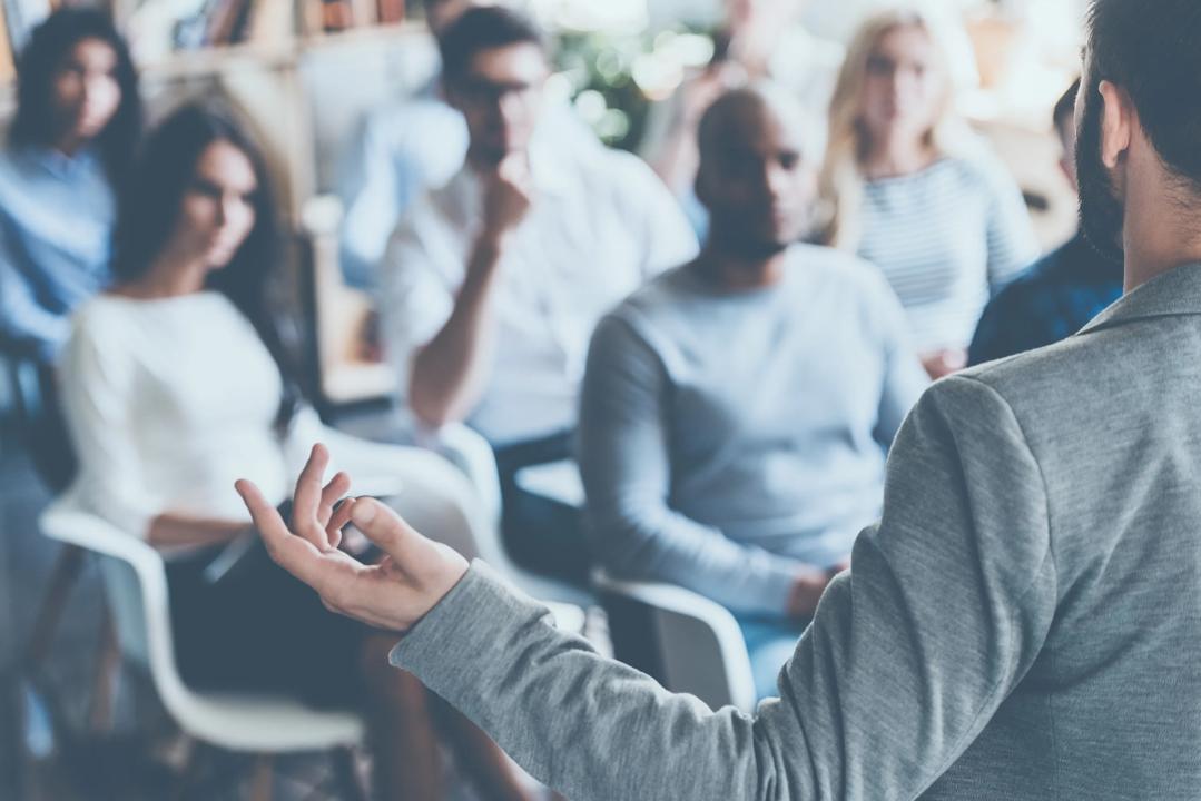 Image of a person talking in front of an audience.