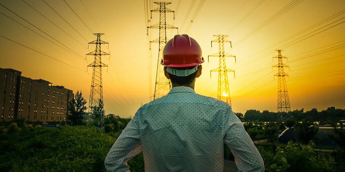 A person with building helmet standing in front of current mast