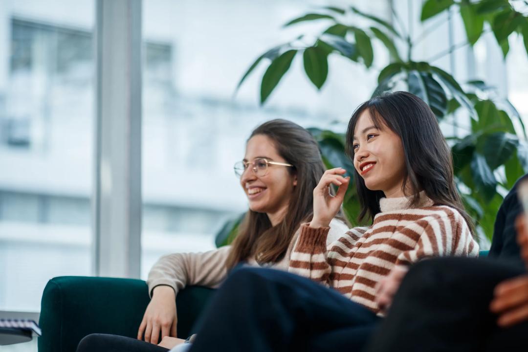 To kvinnelige studenter som sitter på en sofa på campus