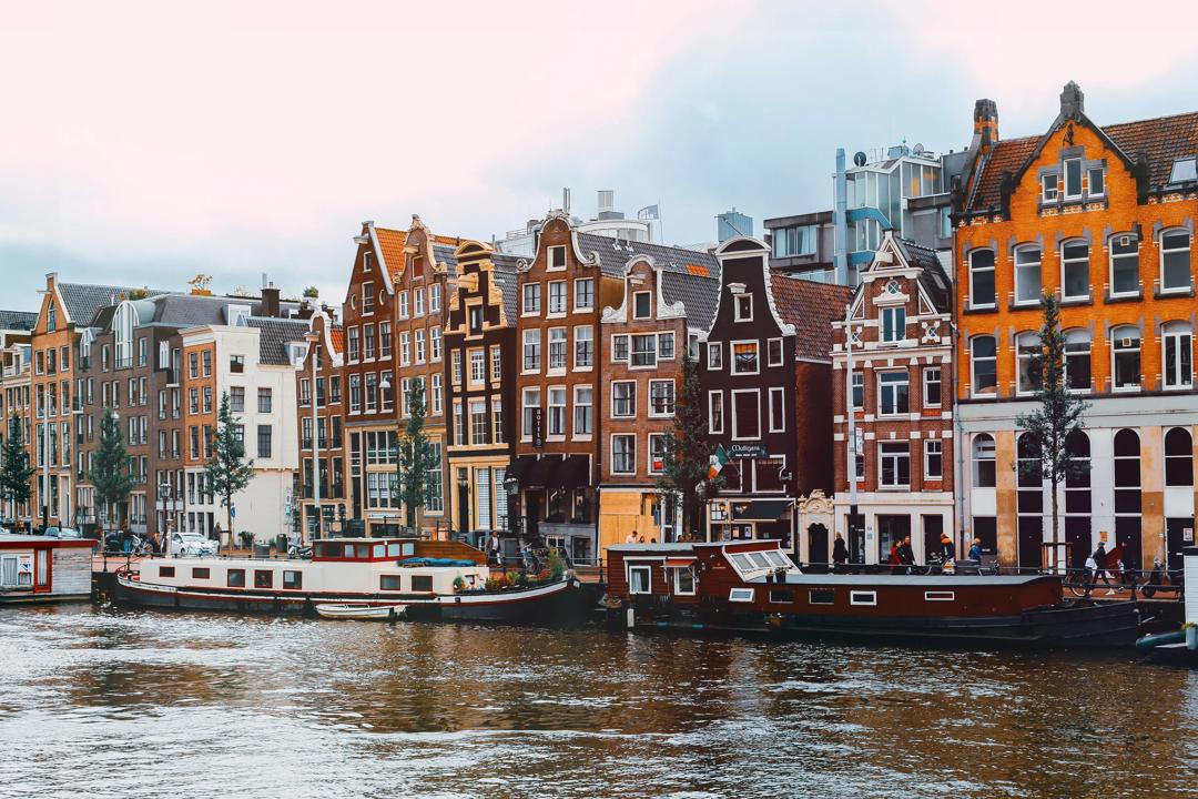 A group of boats that are sitting in the water in Amsterdam, Netherlands.