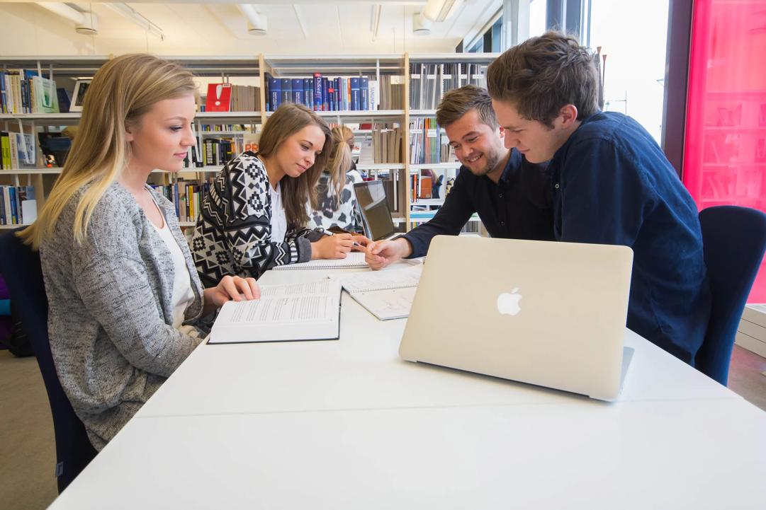 Studenter som sitter å jobber sammen på biblioteket