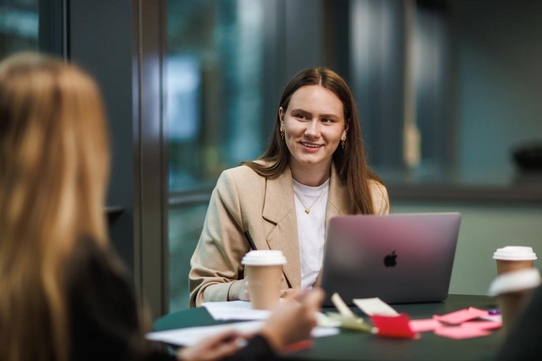Female student talking with other students around a table.