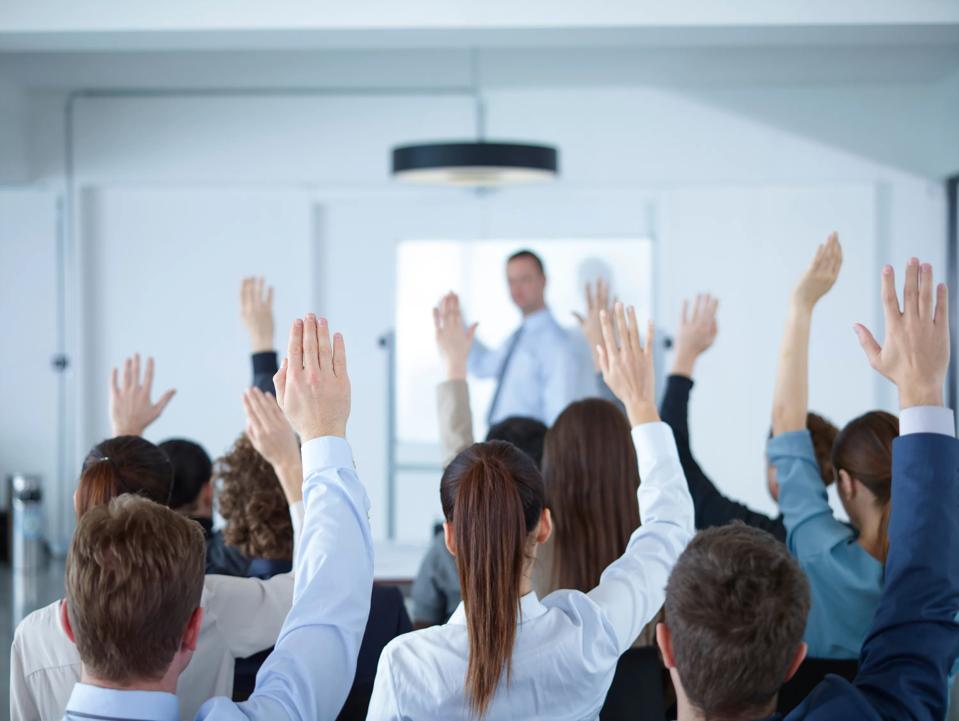 Group of people rising their hands in classroom