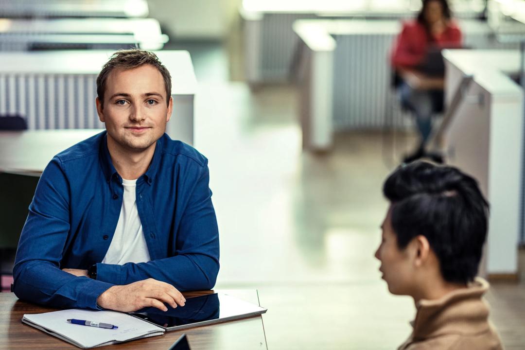 En mannlig student i blå skjorte på campus