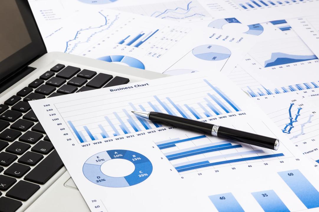 laptop and pen with blue business charts