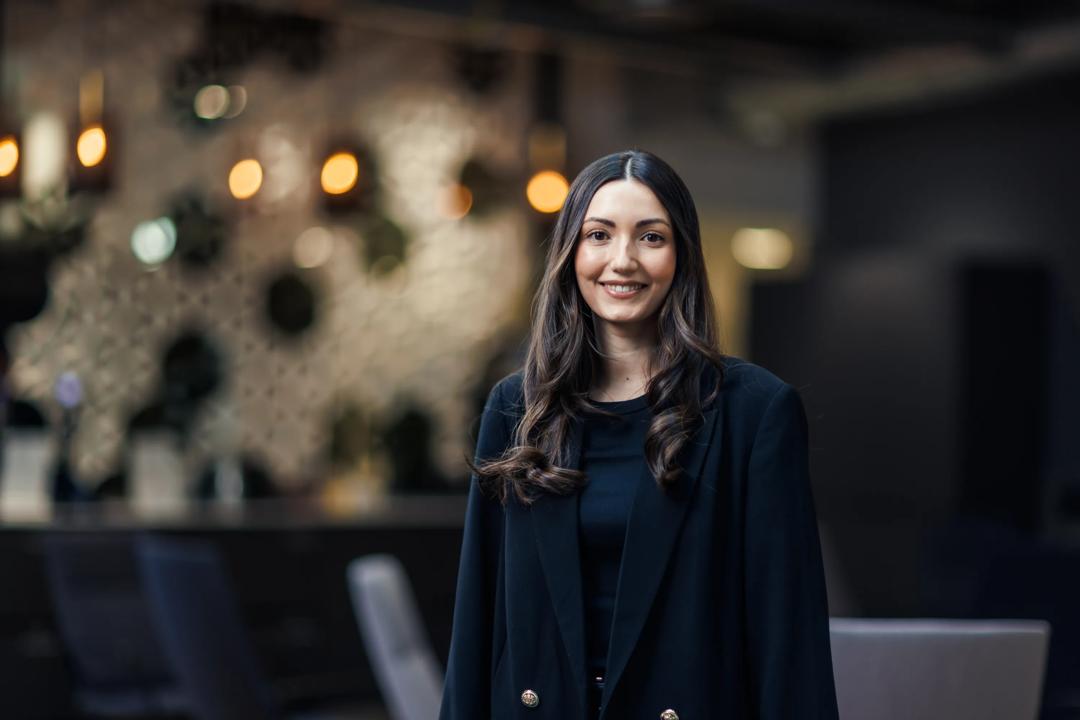 Smilende dame som står med kryssede armer på et kontor