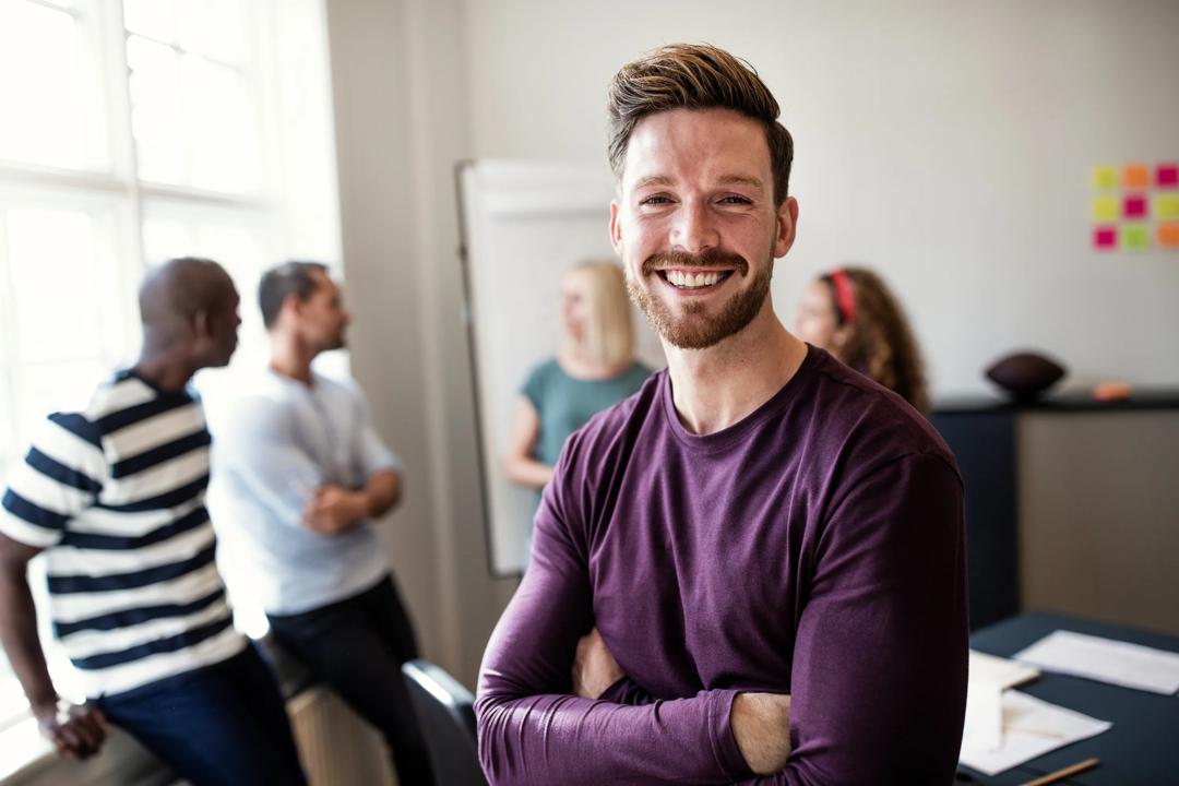 Smilende mann som står foran en gruppe med mennesker