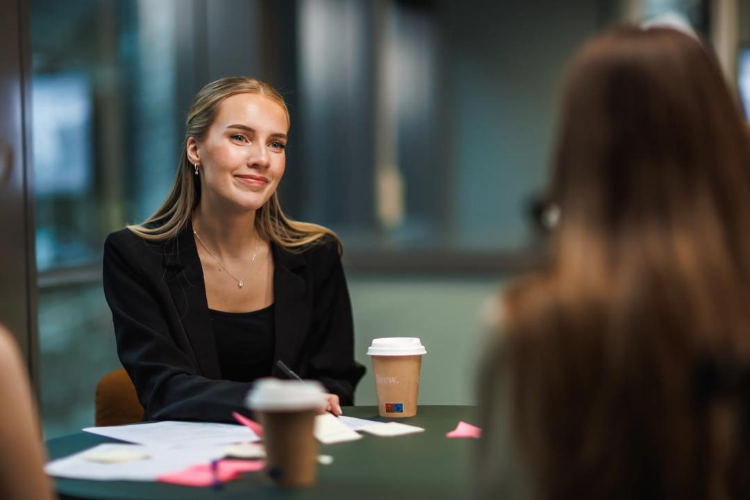 bilde av studenter som samarbeider med en jente som smiler og ser inn i kameraet