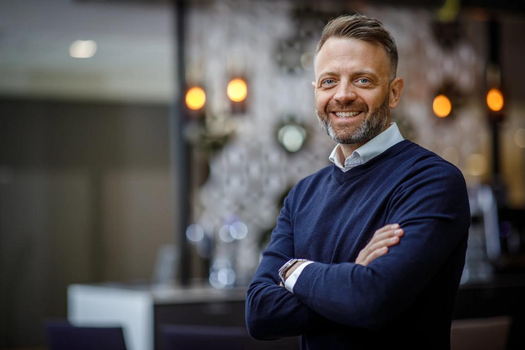 Smilende mann med hendene i kryss