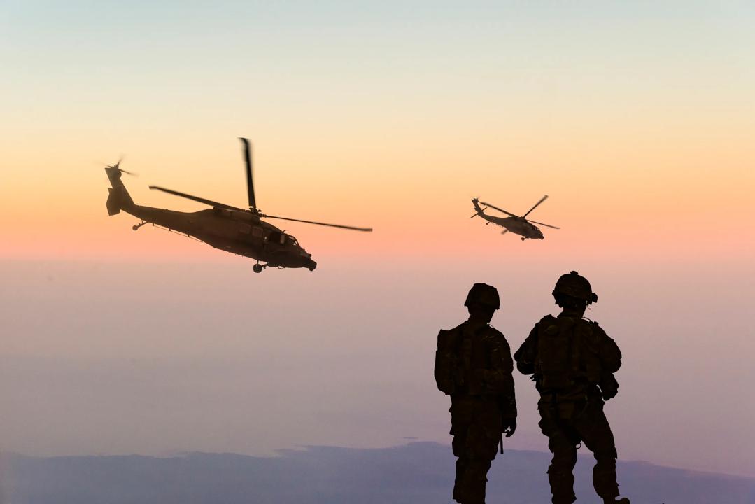 Siluett av helikopter og to mennesker i forgrunnen