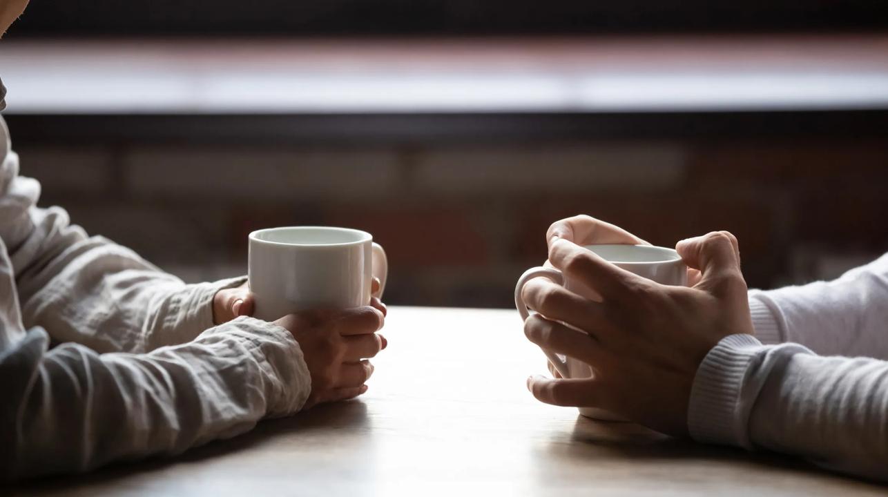 Bilde av to hender som holder rundt hver sin kaffekopp