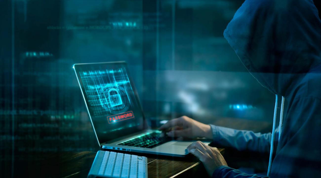 Person med hettegenser over hodet foran en laptop